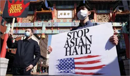  ?? ALEX WONG / GETTY IMAGES VIA AFP ?? Leon Zhang (left) and Chris Tang of McLean, Virginia, take part in a rally on March 21 in Washington in response to the Atlanta spa shootings that left eight people dead, including six Asian women. One of the dead was a Chinese citizen.