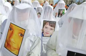  ?? Photo: AFP ?? During a march in New York City, people display portraits of children who were killed in the 2012 school shooting at Sandy Hook Elementary School.