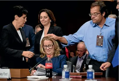  ?? AP ?? Christine Blasey Ford is patted on the head by Keith Kogner as she finishes testifying to the Senate Judiciary Committee on Capitol Hill in Washington.