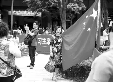  ??  ?? A pro-Beijing supporter (centre) poses for a photo with the Chinese flag in Hong Kong to mark 20 years since the politicall­y divided city was handed back to China by Britian. — AFPphoto