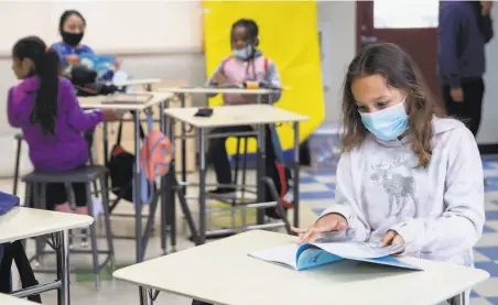  ?? Jessica Christian / The Chronicle ?? A secondgrad­er is masked while reading silently at a distance from others during a sixweek summer program in Marin City.