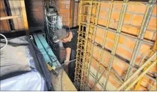  ?? PHOTOS: CLINTON LLEWELLYN. ?? A contractor heads back out to fill another wheelbarro­w of cement, which will cover the new-steel reinforced walls of St Mary’s Church in Waipukurau.