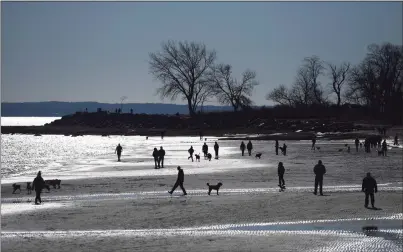  ?? Tyler Sizemore / Hearst Connecticu­t Media ?? Visitors walk and relax on the beach at Greenwich Point Park in Old Greenwich last week. Since the COVID-19 pandemic arrived in the the U.S., Greenwich Point Park has drawn more than the usual number of visitors during the off-season. The park bans out-of-towners and had to turn away 600 cars on New Year’s Day.