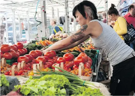  ?? BRUCE DEACHMAN / OTTAWA CITIZEN ?? Emilie Diotte arranges produce at the ByWard Market. Other markets and parking may kill the historic venue.