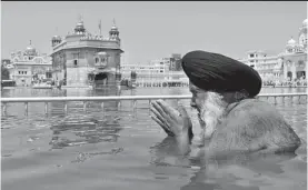  ?? — PTI ?? A devotee takes a dip in the sarovar at the Golden Temple in Amritsar on Thursday, the eve of Baisakhi.