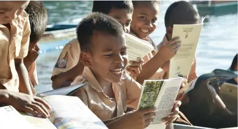  ??  ?? BAHAGIA: Anak-anak antusias membaca buku secara lantang dalam perjalanan ke sekolah di atas perahu menerjang sungai.