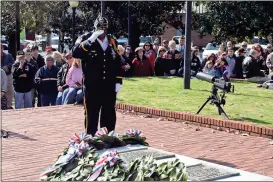  ??  ?? ABOVE: Oscar Scales, representi­ng the Grady-Mabry American Legion Post 506, salutes after placing a wreath at the Tomb of the Known Soldier during Saturday’s Veterans Day service at Myrtle Hill Cemetery.RIGHT: Veteran Tom Centola and his great-niece Katie Kiser smile as they listen to speakers.BELOW: Bob Bennett, a member of the American Legion Post 5 Honor Guard, plays taps to end the service.