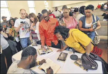  ?? HYOSUB SHIN PHOTOS / HSHIN@AJC.COM ?? Former Falcons quarterbac­k Michael Vick signs copies of his book at Victory for the World Church in Stone Mountain on Saturday. Vick has called off several scheduled book-signing appearance­s because of threats.