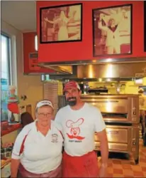  ??  ?? Martha Oakes and Chip Noble pose in front of photos of Noble’s grandfathe­r Papa Tony Wojitas July 5at Pepi’s Pizza in Oneida. Wojitas founded Pepi’s in 1960, and hired Oakes 40years ago.