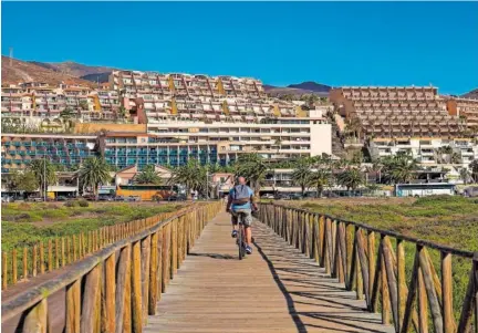  ?? D. DELIMONT (ALAMY / CORDON PRESS) ?? Un hombre monta en bici junto a varios edificios de apartament­os en Fuertevent­ura.