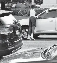  ?? KENNETH K. LAM/BALTIMORE SUN ?? A Baltimore City youth works for tips washing car windshield­s in 2019.