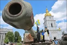  ?? Sergei Supinsky/AFP via Getty Images ?? School graduates stand atop a tank wreck, which is displayed as part of an outdoor exhibition of destroyed Russian military equipment, on Tuesday in the center of Kyiv.