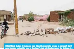  ?? —AFP ?? OMDURMAN, Sudan: A Sudanese man rides his motorbike around a makeshift barricade blocking a street for cars in Khartoum’s twin city Omdurman on the first day of a civil disobedien­ce campaign across Sudan.