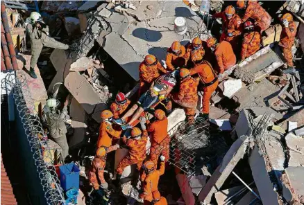  ?? Thiago Gadelha/Diário do Nordeste/AFP ?? Bombeiros retiram sobreviven­te dos escombros de prédio desabado em Fortaleza, nesta terça (15)