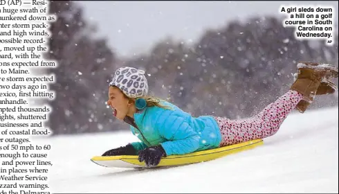  ??  ?? A girl sleds down a hill on a golf course in South Carolina on Wednesday.