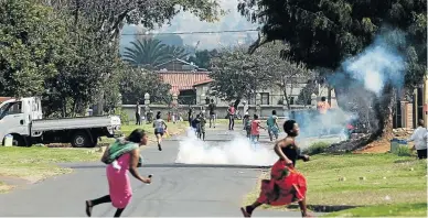  ??  ?? Eldorado Park residents run for cover as police fire teargas and rubber bullets at them.