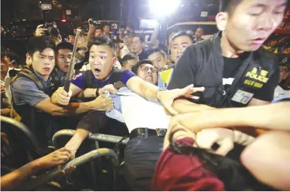  ??  ?? HONG KONG: Protesters scuffle with police officers after clashing as thousands of people march in the streets. — AP