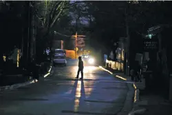  ?? LUIS SÁNCHEZ SATURNO/THE NEW MEXICAN ?? A man crosses the street Tuesday night on a dark area of Canyon Road. Following muggings late last year, City Councilor Joseph Maestas sponsored a resolution calling for lighting upgrades on the popular street.