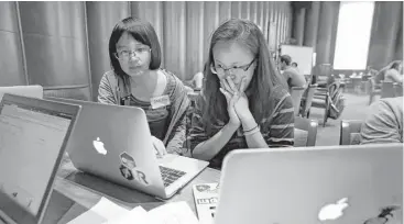  ?? Annie Mulligan ?? Alice Hou and Amanda Shih work together on a laptop at Rice University’s Fondren Library on Saturday.