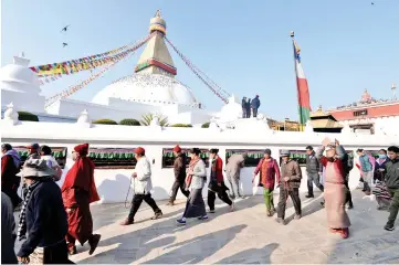  ?? — AFP photo ?? Nepali police stand guard as Tibetans walks past the Bouddhanat­h Stupa in Kathmandu, on the 60th anniversar­y of the 1959 Tibetan uprising against Chinese rule.