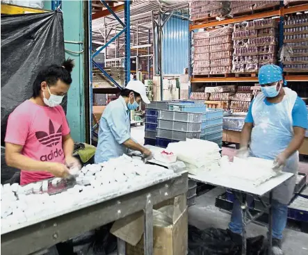  ??  ?? Fall in line: Workers packing car clay bars at a semi-automated production line.
