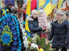  ?? SEAN GALLUP GETTY IMAGES ?? Family members walk among the graves of Ukrainian soldiers killed in fighting against the Russians in eastern Ukraine.