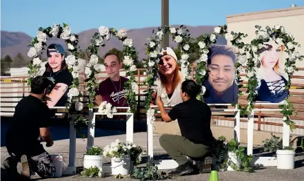  ?? AP ?? Noah Reich, left, and David Maldonado, the Los Angeles co-founders of Classroom of Compassion, put up a memorial with photograph­s of the five victims of a weekend mass shooting at a nearby gay nightclub yesterday in Colorado Springs.