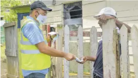  ?? (Photo: Philp Lemonte) ?? In the August 2020 file photo Health and Wellness Minister Dr Christophe­r Tufton (left) gives a face mask to a Clark’s Town resident during a COVID-19 sensitisat­ion walk in Trelawny.