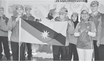  ??  ?? Fatimah (right) and others react as Samsudin (second right) hands over the Sarawak flag to Carrie (left).