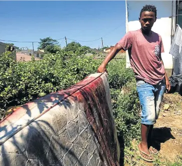  ?? Pictures: JEFF WICKS ?? STAIN: Khulekani Mzila with the mattress on which his brothers had been sleeping when they were shot.