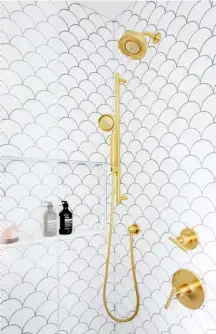  ??  ?? ABOVE Fan-shaped tiles handsomely set off with dark grout and luxe brass fixtures feel chic and fresh. An ample niche shelf can hold an onslaught of soaps and hair products.