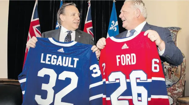  ?? CHRIS YOUNG / THE CANADIAN PRESS ?? Quebec Premier François Legault exchanges hockey jerseys with Ontario Premier Doug Ford following meetings in Toronto on Monday.