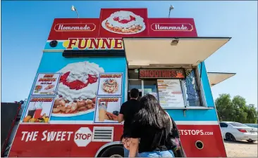  ?? PHOTOS BY TERRY PIERSON — STAFF PHOTOGRAPH­ER ?? Lily Sarabia, 4, keeps her eyes on people behind her in line as her parents, Ernie and Josey Sarabia of Moreno Valley, place an order at The Sweet Stop food truck in the Woodcrest area near Riverside on Wednesday.