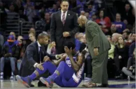  ?? MATT SLOCUM — THE ASSOCIATED PRESS ?? The Sixers’ Joel Embiid, center, is attended to on the court after a head collision with Markelle Fultz. Embiid left early with a facial contusion but reportedly was checked out later at a hospital.