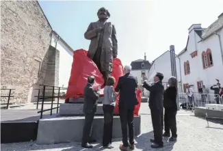  ??  ?? 2018年5月5日，在马克思诞辰200周­年之际，由中国赠送的马克思雕­像揭幕仪式在他的故乡——德国西南部城市特里尔­举行。雕像重约2.3吨，高4.6米，连同基座总高5.5米，由中国雕塑家吴为山创­作。 图为当日，在德国特里尔，嘉宾为马克思雕像揭幕。