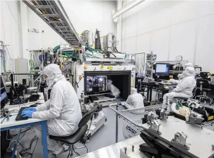  ??  ?? ABOVE Engineers in a clean room at the SLAC National Accelerato­r Laboratory in California monitor and control the custom-built machinery and software used to carefully construct the focal plane