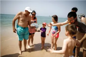  ?? (Amir Cohen/Reuters) ?? BEACHGOERS look at a jellyfish at Zikim near Ashkelon.