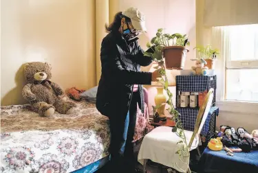  ?? Jessica Christian / The Chronicle ?? Eva Maggard, 70, untangles a plant after arriving at her home in San Francisco’s Tenderloin neighborho­od. Although she has resumed taking walks and some classes, she says,“It’s four walls and a TV.”