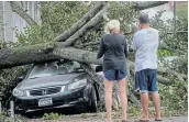  ?? Picture: REUTERS / BRENDAN MCDERMID ?? STORM DAMAGE: People look at a fallen tree on a car in the aftermath of Tropical Storm Isaias in the Rockaway area of Queens in New York City, US.