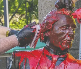  ?? JOHN MORRIS / THE CANADIAN PRESS FILES ?? Workers remove red paint from a Sir John A. Macdonald statue
that was vandalized in Charlottet­own in June.