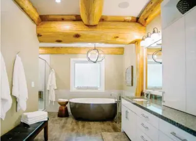  ??  ?? Minera quartz countertop­s continue in the master ensuite where consistent cabinetry and vinyl plank hardwoods anchor the freestandi­ng bath with stainless steel floor mounted fixtures amidst post and beam details.