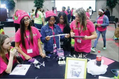  ?? (Matt Hutcheson/News-Times) ?? Members of Team Meterology, made up of sixth graders from across the county, work on their RC car during the Girls Learning about Math and Science conference on Friday.