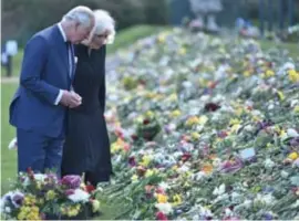  ?? FOTO REUTERS ?? Charles en Camilla bij de bloemenzee die rouwende Britten voor het hek van Buckingham Palace hebben achtergela­ten.
