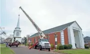  ?? PHOTOS BY BARBARA GAUNTT/CLARION LEDGER ?? TOP: First Baptist Church of Rolling Fork member Roger Jones, of Anguilla, adds speaker mechanisms to the speaker cones inside the new church steeple before it was scheduled to be raised onto the church roof Friday. The EF-4 tornado that ripped through the small Delta town on March 24, 2023, took down the previous steeple. The chimes are scheduled to ring for the first time at 8:03 p.m., Sunday, one year to the minute the tornado hit. ABOVE: The new steeple for First Baptist Church of Rolling Fork is lifted off the flatbed truck before it was scheduled to be placed atop the church roof.