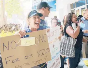  ?? MARTA LAVANDIER/AP ?? Joann Marcus of Fort Lauderdale, left, cheers as she listens to the Broward School Board’s emergency meeting Wednesday in Fort Lauderdale, Florida.