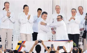  ?? FERNANDO VERGARA/ASSOCIATED PRESS ?? Colombia’s President Juan Manuel Santos, front left, and top commander of the Revolution­ary Armed Forces of Colombia Rodrigo Londono shake hands after a peace pact.