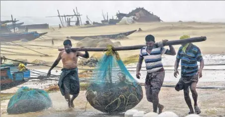  ?? PTI ?? Fishermen clear the coast as Cyclone Titli, with a wind speed of up to 150 kilometers an hour, hits Odisha’s Gopalpur on Thursday.