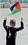  ?? ?? A Palestinia­n youth waving the national flag flashes the middle finger at Israeli security forces in the occupied West Bank. (AFP)