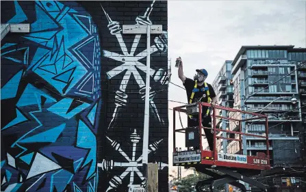  ?? CHRISTOPHE­R KATSAROV THE CANADIAN PRESS ?? Anthony Ricciardi spray paints the eastern facade of a commercial establishm­ent on Bathurst Street in Toronto.