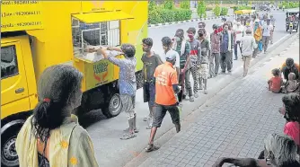  ?? HIMANSHU VYAS/HT ?? People queue up to receive food packets from a charity van during the ongoing lockdown in Jaipur.